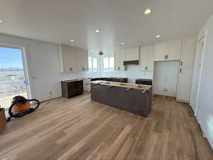 Dual tone kitchen with two tone color scheme, a kitchen island, recessed lighting, and light wood-style floors