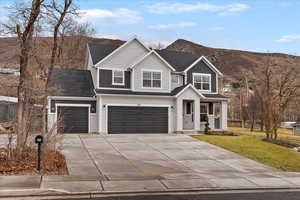 Traditional-style house featuring concrete driveway, a front yard, a mountain view, and board and batten siding