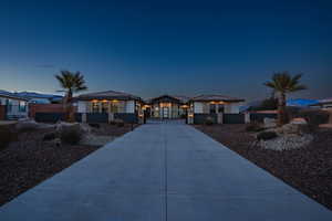 Prairie-style home with stone siding, a fenced front yard, a tile roof, and concrete driveway