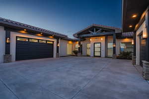 View of front of house with stucco siding, concrete driveway, a tile roof, and an attached garage