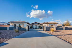 View of front of house with a gate, stone siding, a fenced front yard, and a tiled roof