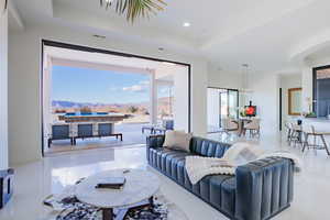 Living area featuring a mountain view, a tray ceiling, recessed lighting, and light tile patterned floors
