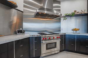 Two tone kitchen with luxury stove, light tile patterned flooring, open shelves, modern cabinets, and light stone countertops