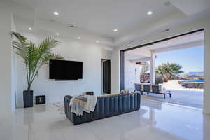 Living room featuring light tile patterned flooring, a raised ceiling, and recessed lighting