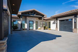 View of front of house with a tiled roof, stucco siding, driveway, an attached garage, and stone siding