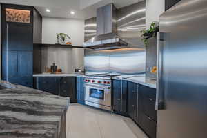 Kitchen featuring stainless steel appliances, ventilation hood, modern cabinets, light stone counters, and light tile patterned flooring