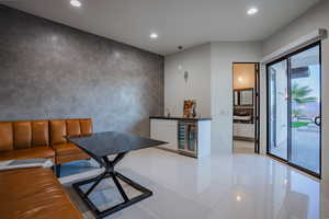 Dining space with recessed lighting, beverage cooler, bar with sink, an accent wall, and light tile patterned floors