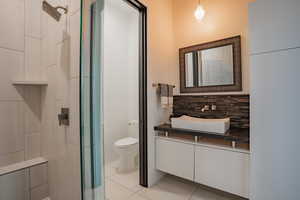 Full bathroom featuring vanity, light tile patterned floors, a shower, and backsplash