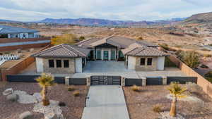 View of front of property featuring stone siding, a gate, a fenced front yard, and concrete driveway