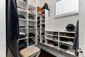 Walk in closet with dark wood-type flooring