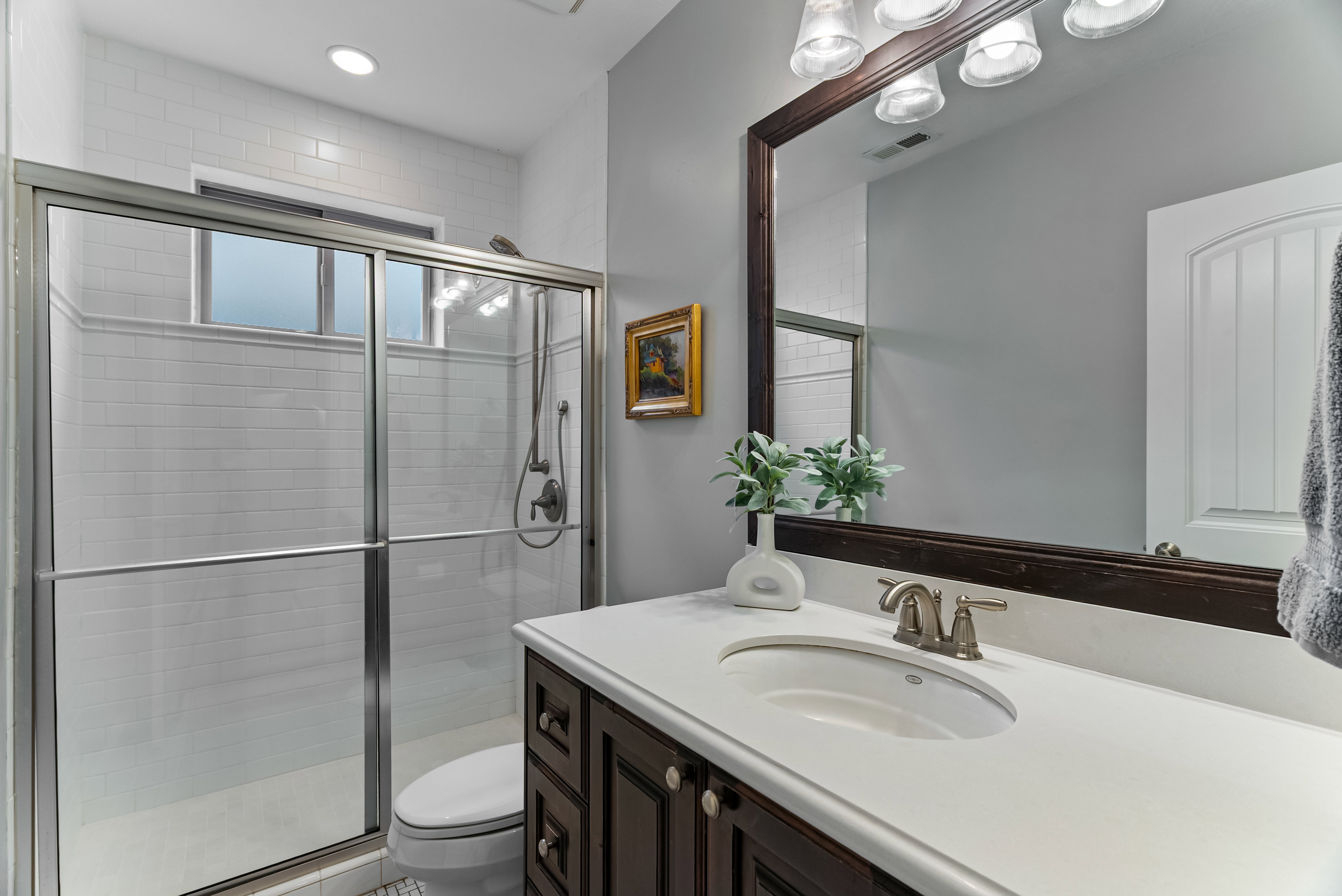 Bathroom with a stall shower, vanity, and recessed lighting