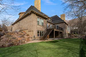 Rear view of property with a chimney, brick siding, a yard, and a wooden deck