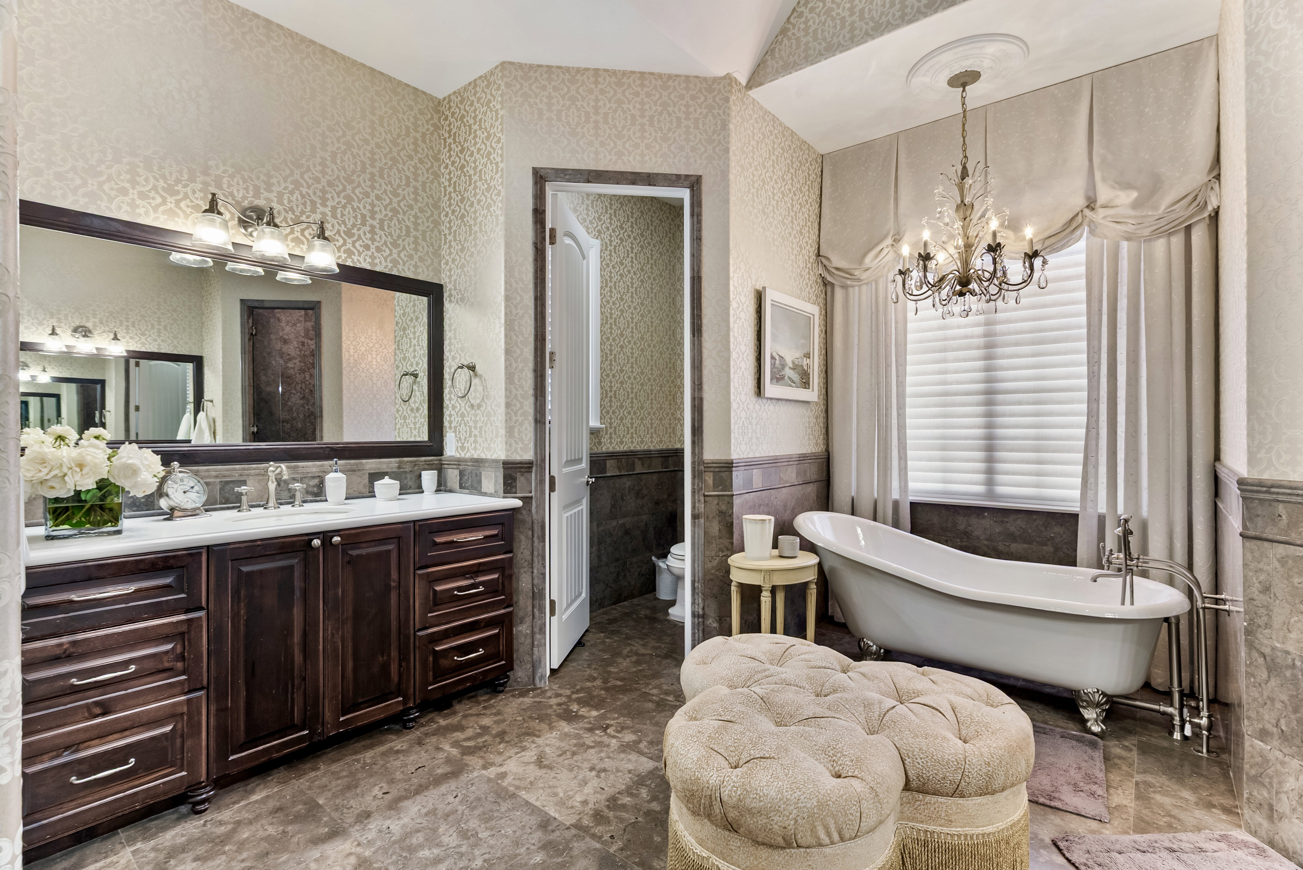 Bathroom featuring a wainscoted wall, vanity, hanging lights, a freestanding tub, and wallpapered walls
