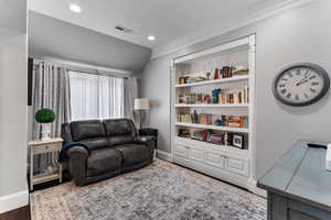 Living area with lofted ceiling, crown molding, recessed lighting, built in features, and wood finished floors