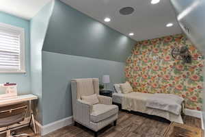 Bedroom featuring wallpapered walls, vaulted ceiling, dark wood-type flooring, an accent wall, and recessed lighting