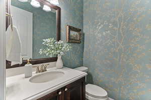 Half bath featuring vanity and wallpapered walls