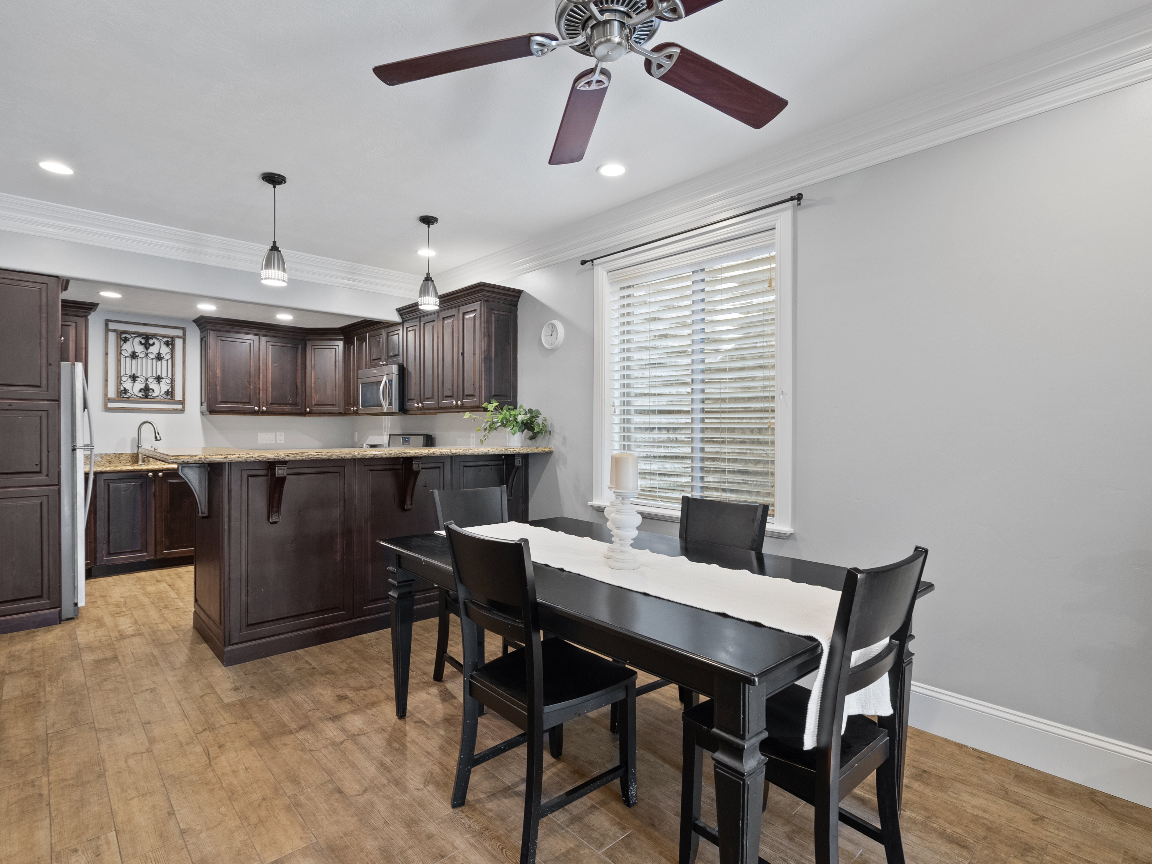 Apartment Kitchen and dining area featuring wood-finish flooring, dark wood cabinetry, granite countertops, and recessed lighting