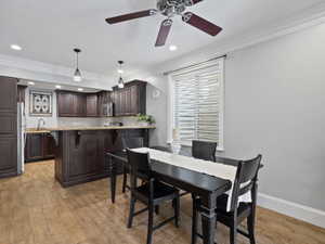 Apartment Kitchen and dining area featuring wood-finish flooring, dark wood cabinetry, granite countertops, and recessed lighting