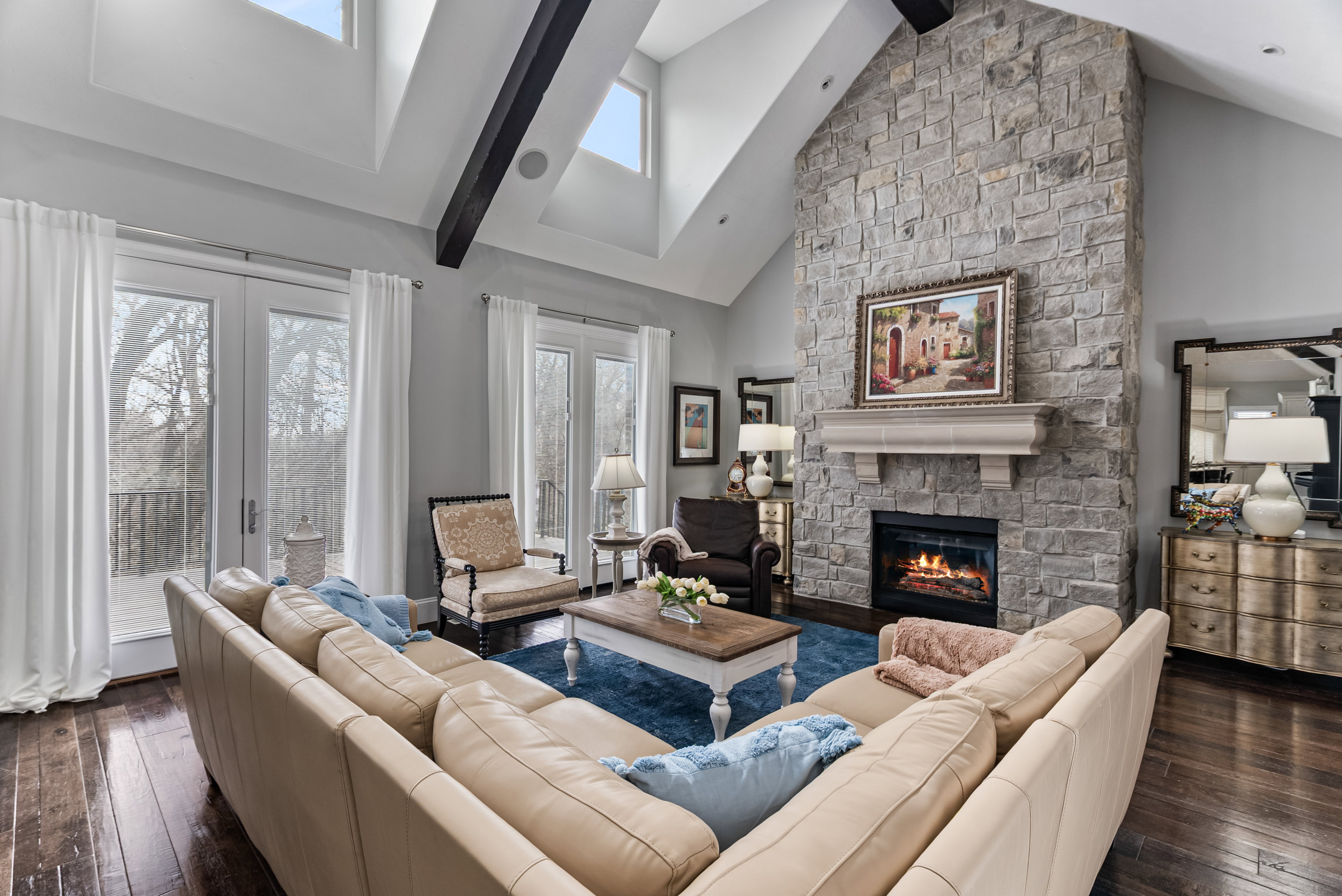 Living area featuring dark wood-type flooring, a stone fireplace, lofted ceiling, and plenty of natural light