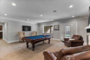Playroom with light carpet, recessed lighting, billiards table, ornamental molding, and a fireplace