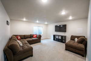 Carpeted living area with a textured ceiling and baseboards