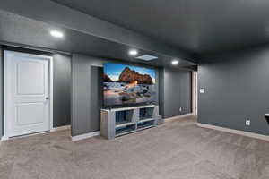 Home theater featuring light colored carpet, recessed lighting, and a textured ceiling