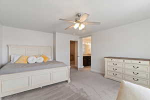 Bedroom featuring ensuite bath, a ceiling fan, and light colored carpet