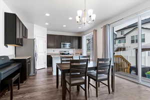 Dining space with suspended lighting and dark wood-style flooring