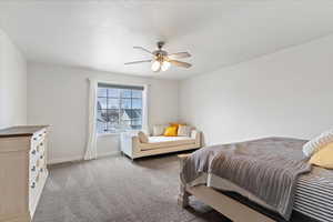 Bedroom with light colored carpet, a ceiling fan, and a textured ceiling