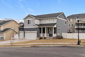 Traditional-style home featuring covered porch, driveway, a garage, and stucco siding