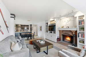 Living room with built in features, light tile patterned flooring, and a fireplace