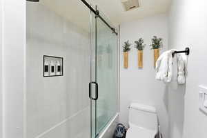 Bathroom with toilet and enclosed tub / shower combo