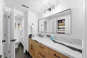 Full bathroom featuring dark tile patterned flooring, vanity, and a textured ceiling