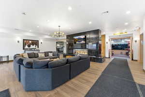 Living room featuring light wood-type flooring, a chandelier, and a fireplace