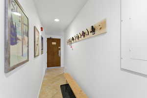 Hall featuring light tile patterned floors, electric panel, and recessed lighting
