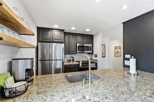 Kitchen featuring stainless steel appliances, light stone counters, recessed lighting, and open shelves