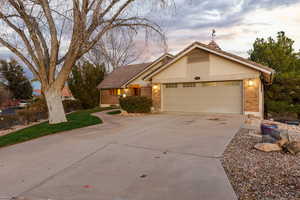 View of front of house featuring brick, driveway, a tile roof, an attached garage, and a yard