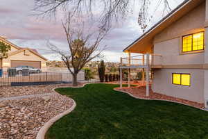 Yard at dusk featuring a deck and an lush pool sized yard