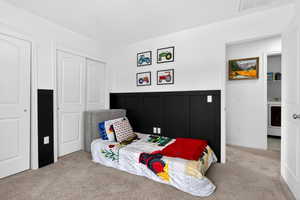 Carpeted bedroom with wainscoting, washer / clothes dryer, and a decorative wall