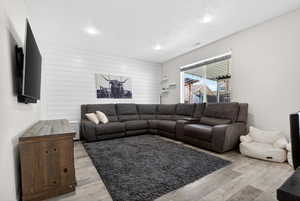 Living room with light wood-type flooring, wooden walls, and recessed lighting