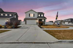 Traditional home featuring stone siding, an attached garage, concrete driveway, and a residential view