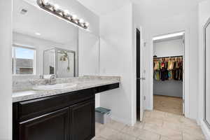 Full bathroom featuring a stall shower, vanity, and a spacious closet