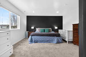 Bedroom with an accent wall, light carpet, and wood walls