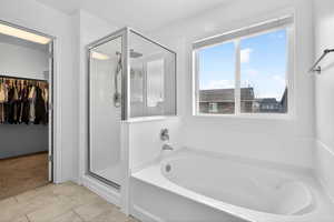 Bathroom with a walk in closet, a stall shower, and a garden tub