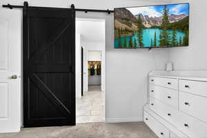 Hall featuring light carpet, a barn door, and light tile patterned floors