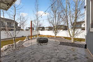 Fenced backyard featuring a residential view, a patio area, and a fire pit