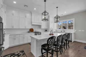 Kitchen with a kitchen bar, white cabinetry, and a center island