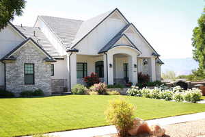 View of front of house featuring brick siding, a front yard, board and batten siding, and a porch