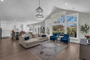 Living area with a high ceiling, dark wood-style flooring, and suspended lighting