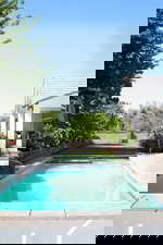 Swimming pool with a water slide, a patio area, and a fenced backyard